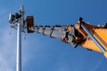 Crane with telescopic boom lift used as an aerial working platform. Worker install cellular base station with transmitters 3G, 4G