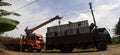 The crane truck lifts the container onto the truck