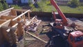 Crane and workers at construction of wooden house. Clip. Top view of working process with team of workers to build