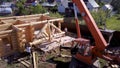 Crane and workers at construction of wooden house. Clip. Top view of working process with team of workers to build