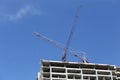 Crane working on a building under construction in day time. Royalty Free Stock Photo