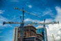 Cranes on modern skyscraper construction in city at sunny day with blue sky