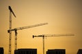 Cranes at sunset. Industrial construction cranes and building silhouettes over sun at sunrise. Royalty Free Stock Photo