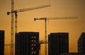 Cranes at sunset. Industrial construction cranes and building silhouettes over sun at sunrise. Royalty Free Stock Photo