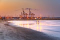 Cranes at sunset with sandy beach and reflections in the foreground at  Larnaca port, Cyprus island Royalty Free Stock Photo