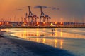 Cranes at sunset with sandy beach and reflections in the foreground at  Larnaca port, Cyprus island Royalty Free Stock Photo