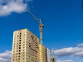 Cranes work at a construction site. New brick houses under construction against the blue sky Royalty Free Stock Photo