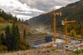 Cranes working on construction site in forested mountains. Multiple tower cranes operate at a construction site in a forested Royalty Free Stock Photo