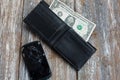 Crashed black smartphone is lying in an empty black leather wallet. One dollar in the purse. No money to buy a new phone. Poverty Royalty Free Stock Photo