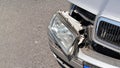 Crashed car, detail on front headlight, glass not broken, hanging from dented bumper plates Royalty Free Stock Photo