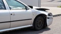 Crashed car standing on road next to curb, side view with demolished front and used airbag inside visible