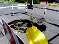 Collapsed asphalt road surface with big crater below surrounded by striped wooden barrier Royalty Free Stock Photo