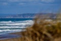 Crashing surf on beautiful Pacific Ocean against a bright blue sky with white cresting waves behind brown grass