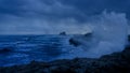 a crashing wave on the rocks of a shore line under a dark sky Royalty Free Stock Photo