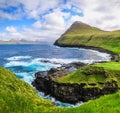 Crashing waves and green hillside of Gjogv in the Faroe Islands