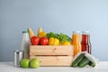 Crate with fresh vegetables and other products on wooden table against light blue background Royalty Free Stock Photo