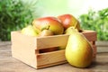 Crate with ripe juicy pears on brown wooden table against blurred Royalty Free Stock Photo
