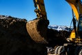 The excavator in the process of work digs out the earth and pours it onto the site. Royalty Free Stock Photo