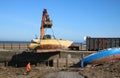 Crawler excavator removing boat wrecks from shore