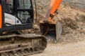 Crawler industrial machine excavator with a bucket on the background of a pile of sand at a construction site Royalty Free Stock Photo