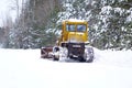 Crawler Tractor grader cleans snow on a forest road. Royalty Free Stock Photo
