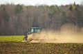 Crawler Tractor plowing ploughing field with Harrow in Spring on Farm with Dust Clouds