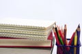 Crayon or colored pencils in box with side stack of books and school supplies. Concept of study and office. Royalty Free Stock Photo