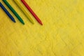 Crayons, blue, green, yellow and red at the upper left corner on yellow