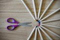 Crayons with colored tips arranged in a circle and open children`s purple scissors Royalty Free Stock Photo