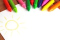 Crayons lying on a paper with painted children's drawing Royalty Free Stock Photo