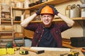 Handsome smiling young man working in carpentry workshop at wooden table place with piece of wood