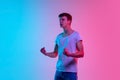 Young caucasian man`s portrait on gradient blue-pink studio background in neon light Royalty Free Stock Photo