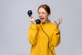 Crazy angry young woman in stylish yellow sweater talking on retro phone and screaming in handset. Royalty Free Stock Photo