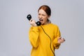 Crazy angry young woman in stylish yellow sweater talking on retro phone and screaming in handset. Royalty Free Stock Photo