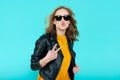 Crazy beautiful rock Girl in leather jacket and black sunglasses. Punk is not dead. Young woman making peace sign hand gesture.