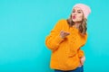 Crazy beautiful trendy girl in colorful clothes and pink beanie hat blowing a kiss. Attractive cool young woman portrait.