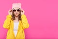 Crazy beautiful trendy girl in colorful clothes and pink beanie puckering lips and holding sunglasses.