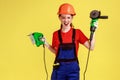 Crazy builder woman holding grinding saw and fretsaw in hands, having crazy facial expression. Royalty Free Stock Photo