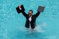 Crazy business man in a business suit works for a laptop standing in the water in pool. Remote work. Crazy freelancer Royalty Free Stock Photo