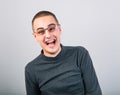 Crazy casual laughing man in eye glasses with wide open mouth on blue background. Closeup