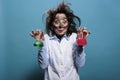 Crazy chemist holding glass flasks filled with toxic chemical compounds after laboratory explosion.