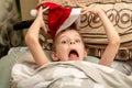 Crazy Christmas. A boy in a Santa hat is lying in bed making faces Royalty Free Stock Photo