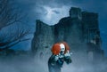 Crazy clown with a balloon in a gloomy scene of an old castle