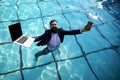 Crazy comic business. Funny businessman in suit with laptop and mobile phone on swimming pool.