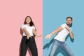 Young emotional man and woman on pink and blue background