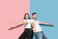 Young emotional man and woman on pink and blue background