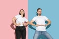 Young emotional man and woman on pink and blue background