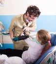 Crazy dentist treats teeth of the unfortunate patient. The patient is terrified.