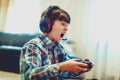 Crazy dependent kid shouting while playing mass multiplayer video game online Royalty Free Stock Photo