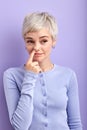 Crazy funny adult woman picking out boogers, drilling nose, looking at side